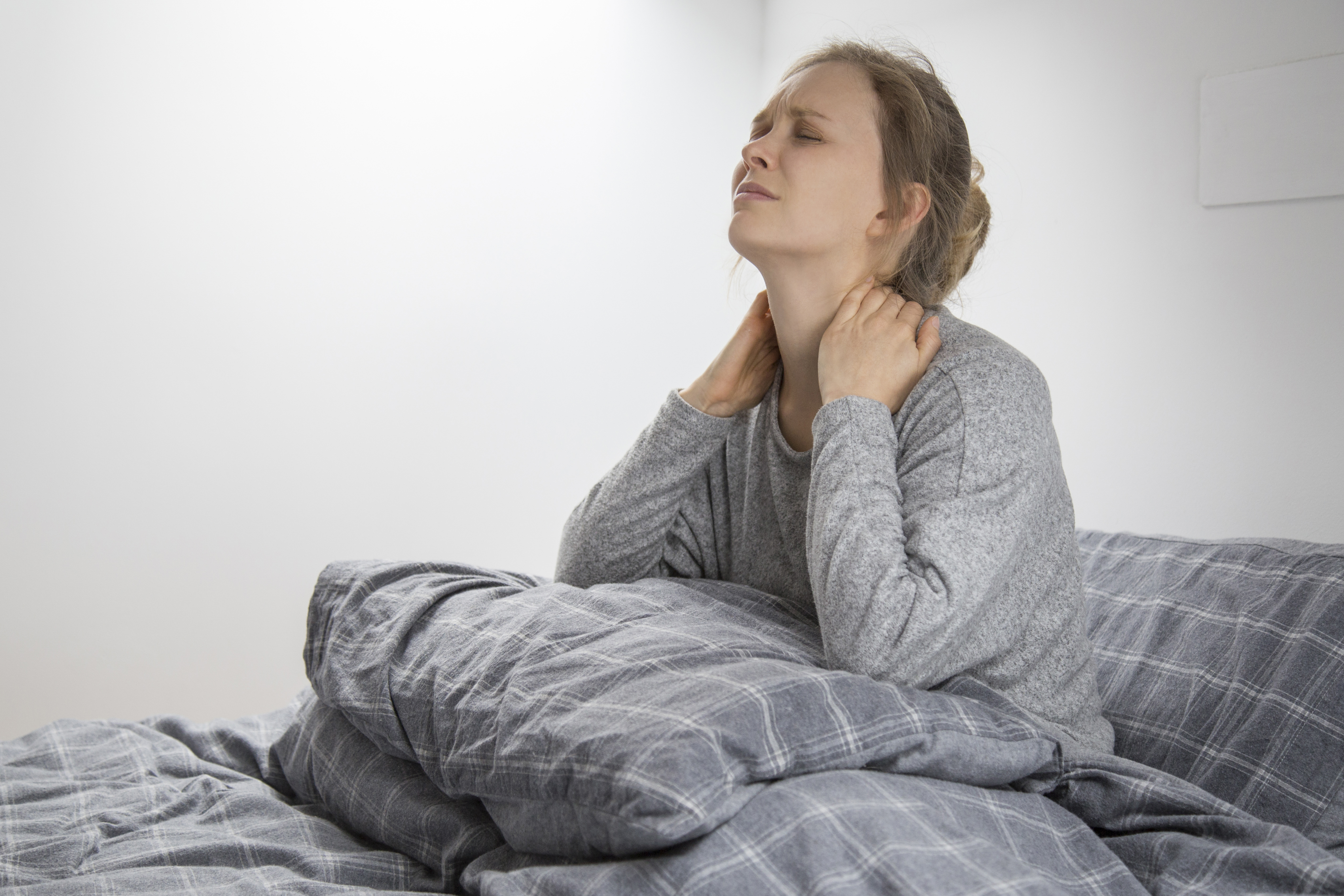 Dolori cervicali: donna che si sveglia con dolori al collo